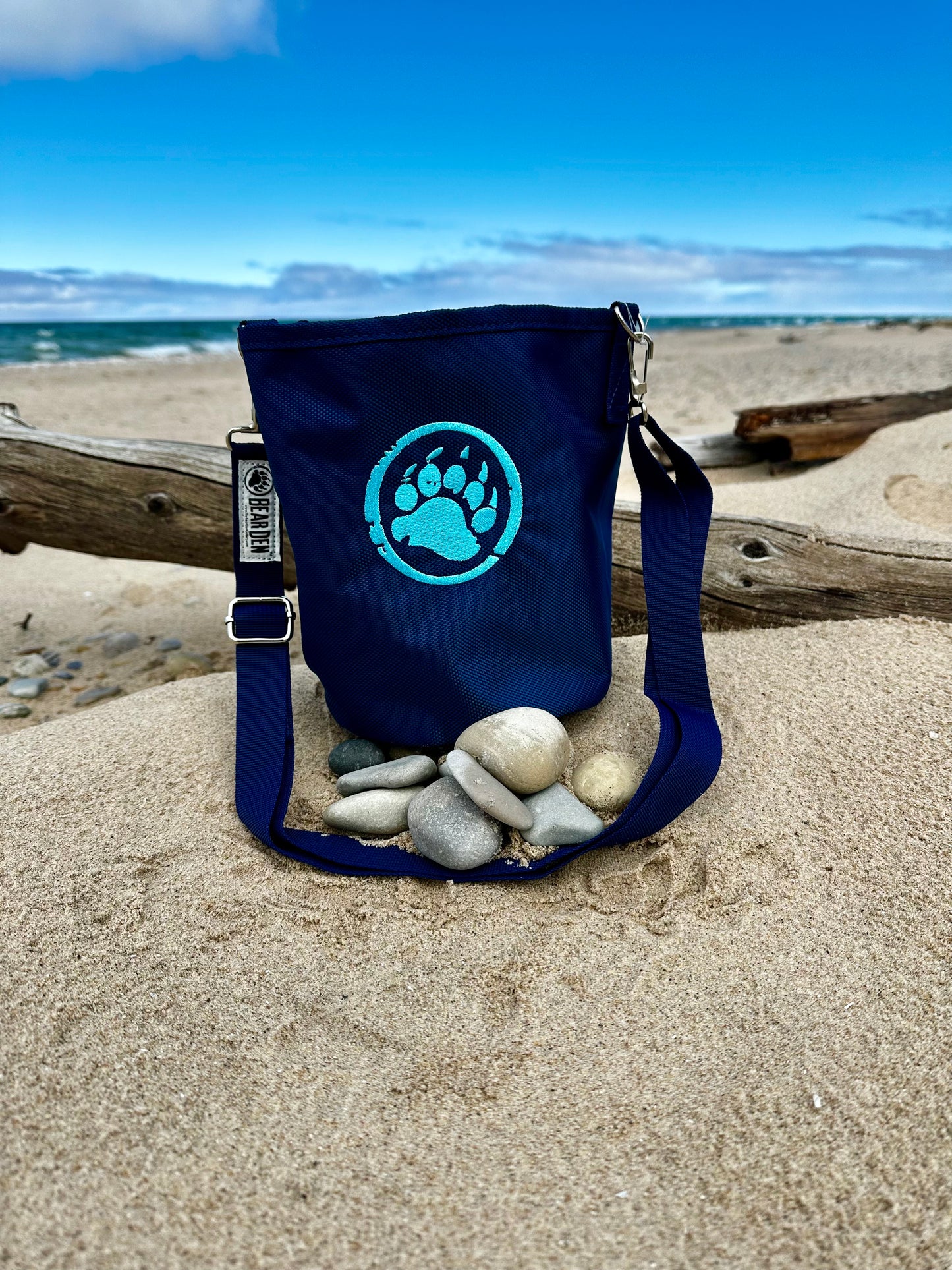 Navy blue bag with a paw print design on a sandy beach